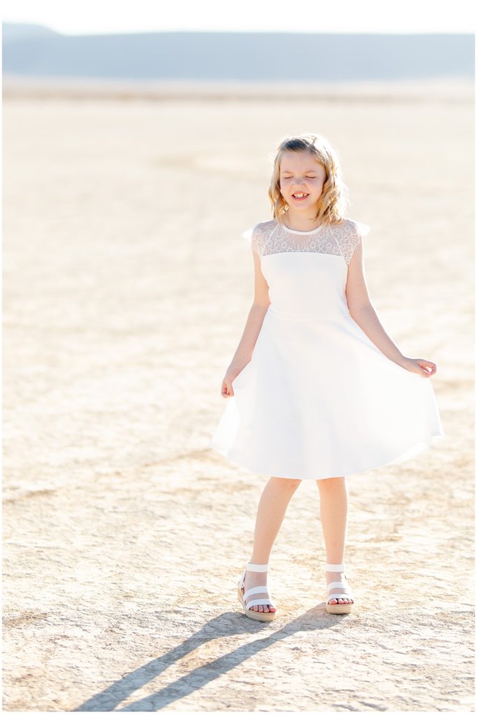 White dress, little girl twirling on dry lake bed